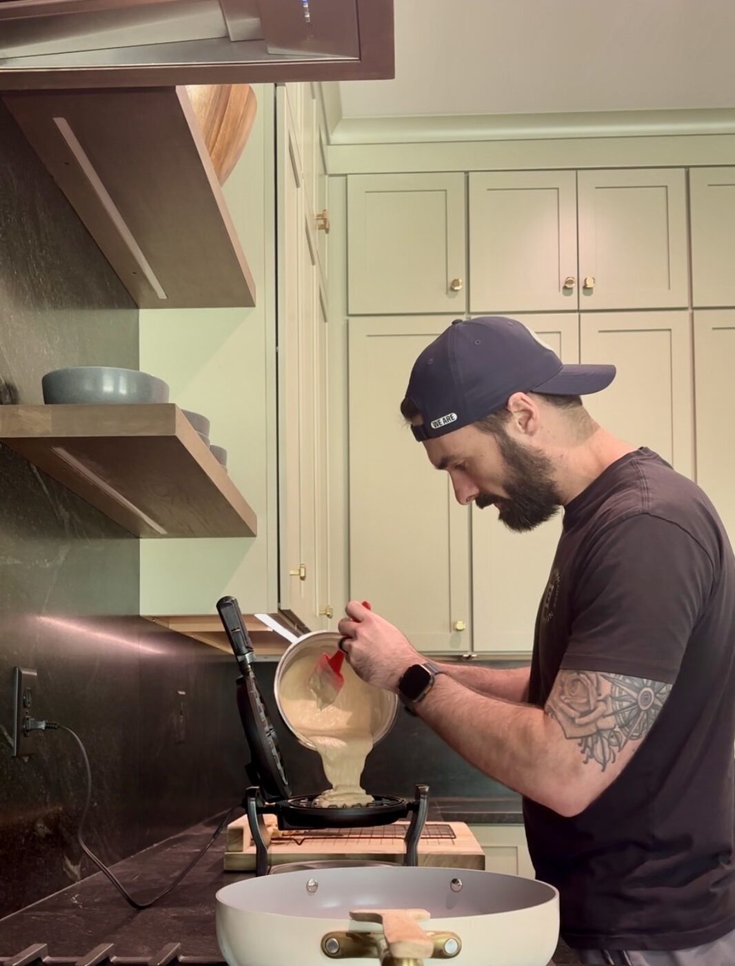 Blake pouring batter into the waffle iron in the home kitchen