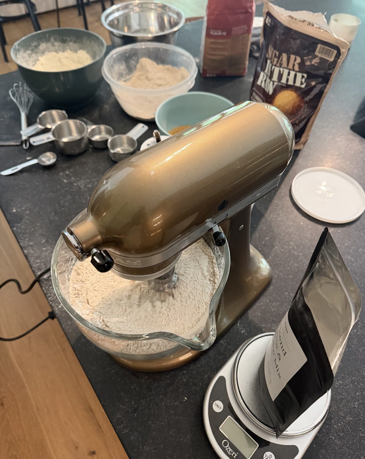 Overhead view of the stand mixer full of dry mix, bowls and scale on the counter