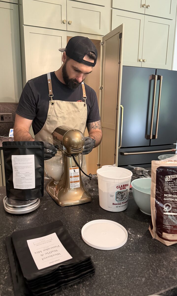 Blake at the stand mixer surrounded by ingredients, making batches of mix to bag
